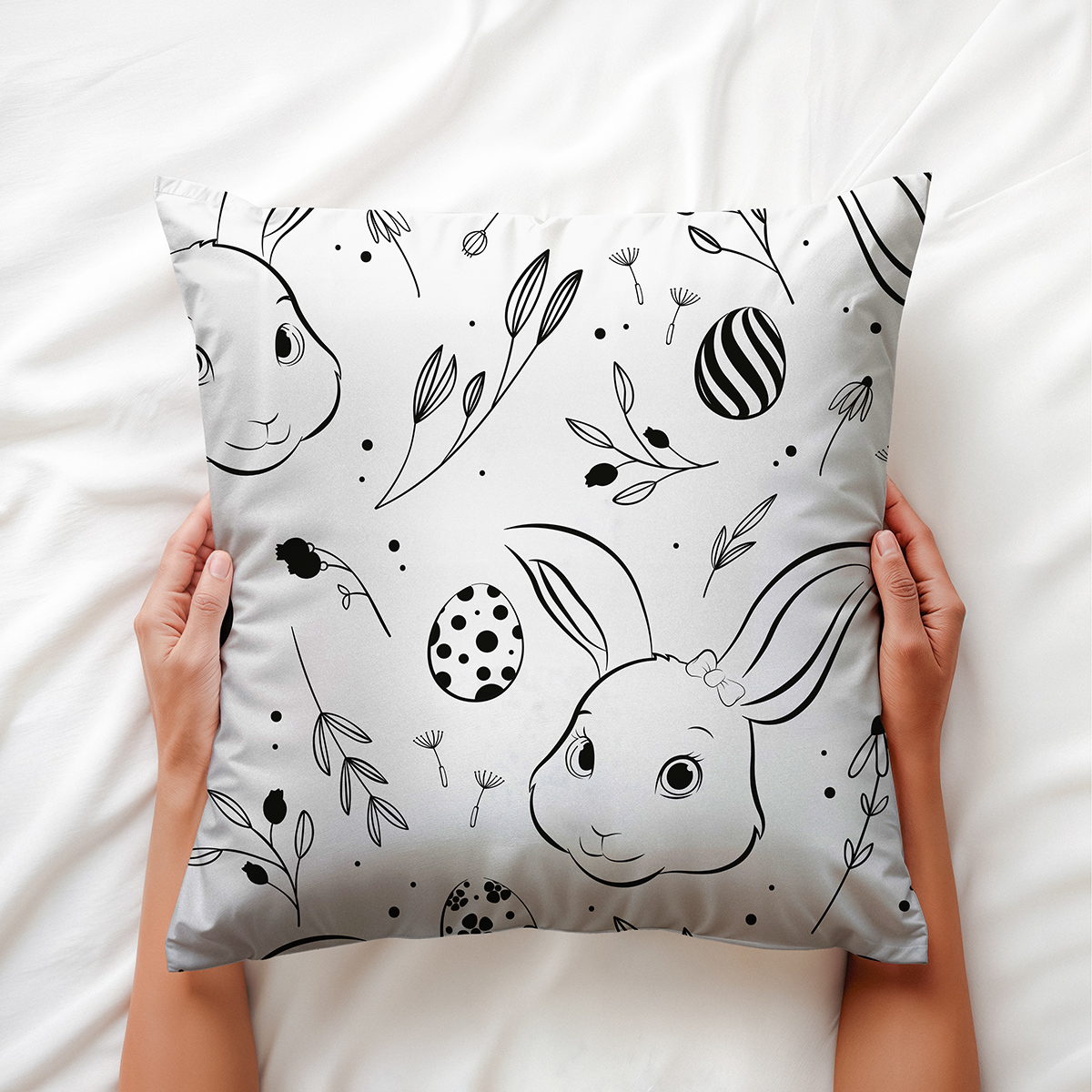 dłonie trzymające poduszkę z motywem króliczków i pisanek, ujęcie z góry