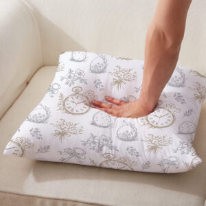 Ręka naciskająca poduszkę, widoczna sprężystość i dekoracyjny motyw z zegarami i kokardkami