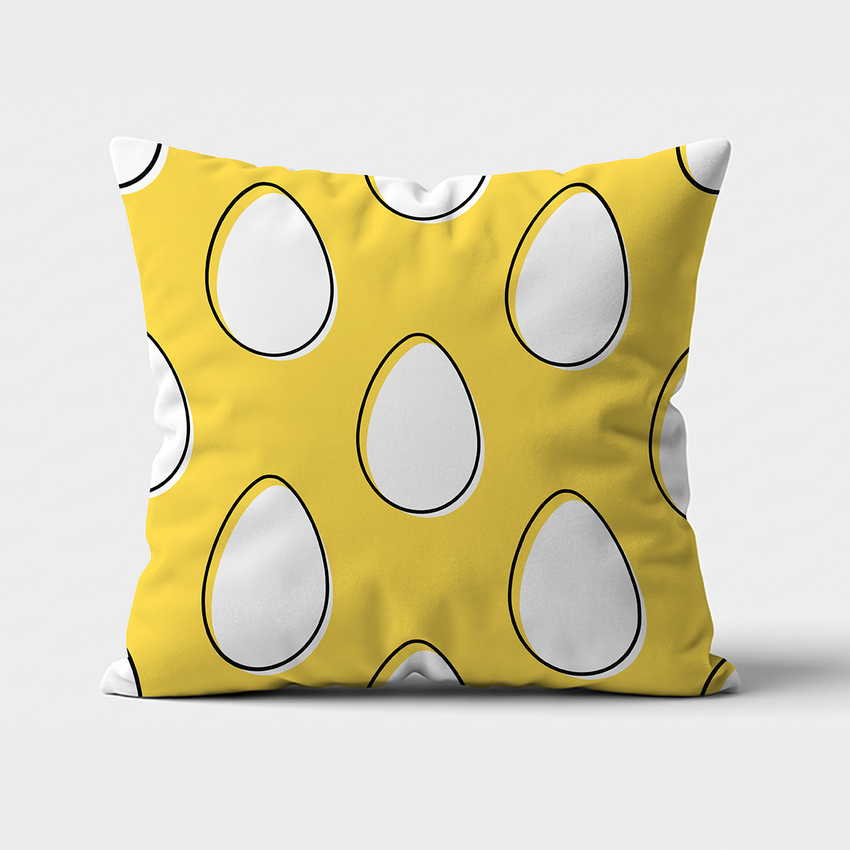 Przód poduszki na białym tle z żółtym tłem i dużymi białymi pisankami z czarną obwódką