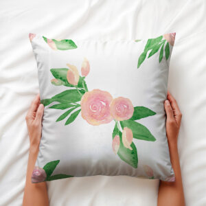 Osoba trzyma miękką poduszkę z różanym wzorem, widoczne pąki i liście