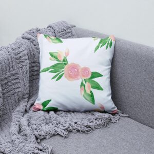 Aranżacja poduszki na szarej sofie obok plecionego koca, subtelny różowo-zielony dekor