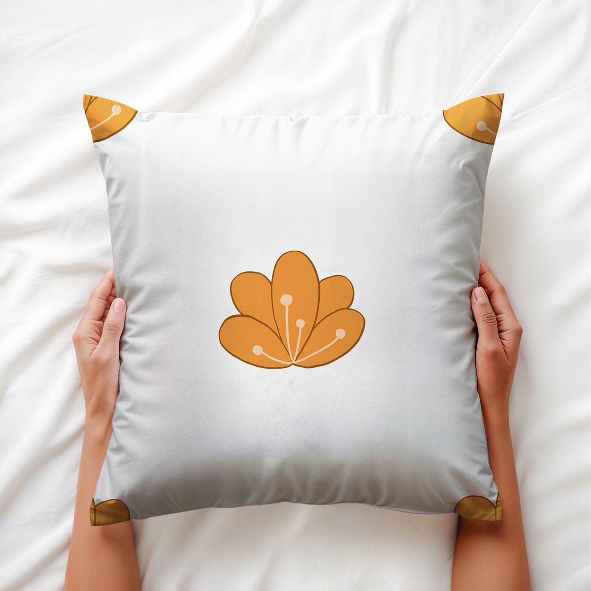 Widok z góry z dłońmi trzymającymi poduszkę, pokazujący główny motyw i narożne pomarańczowe akcenty