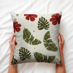 Zbliżenie na poduszkę trzymaną w dłoniach, detal nadruku liści i kwiatu hibiskusa