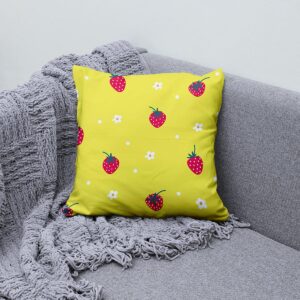 Poduszka dekoracyjna z truskawkami na szarej kanapie obok pledu — detal wzoru i faktury