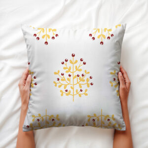 Zbliżenie dłoni trzymającej miękką poduszkę z motywem gałązek i jagód, detal tkaniny