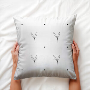 poduszka trzymana w dłoniach, zbliżenie na subtelny motyw listków i rozmieszczone kropki