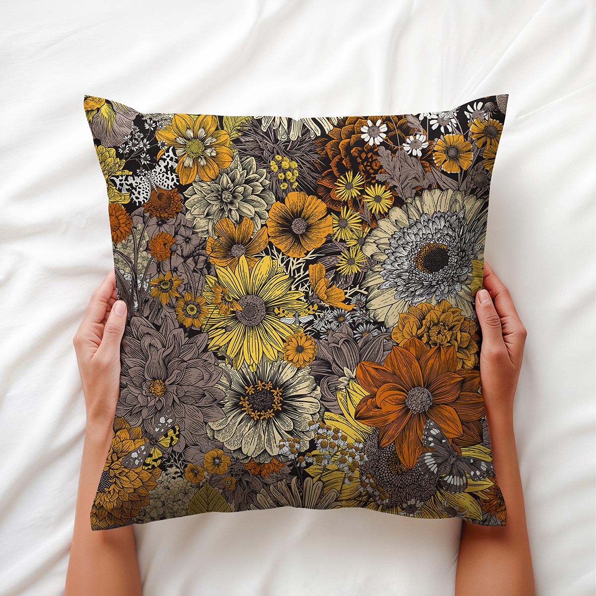 ręce trzymające poduszkę na białej pościeli, detal rysunkowego wzoru kwiatowego