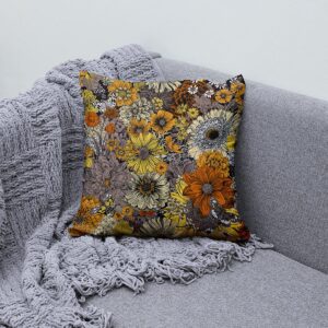 poduszka na szarej kanapie obok pledu, aranżacja wnętrza z motywem kwiatowym