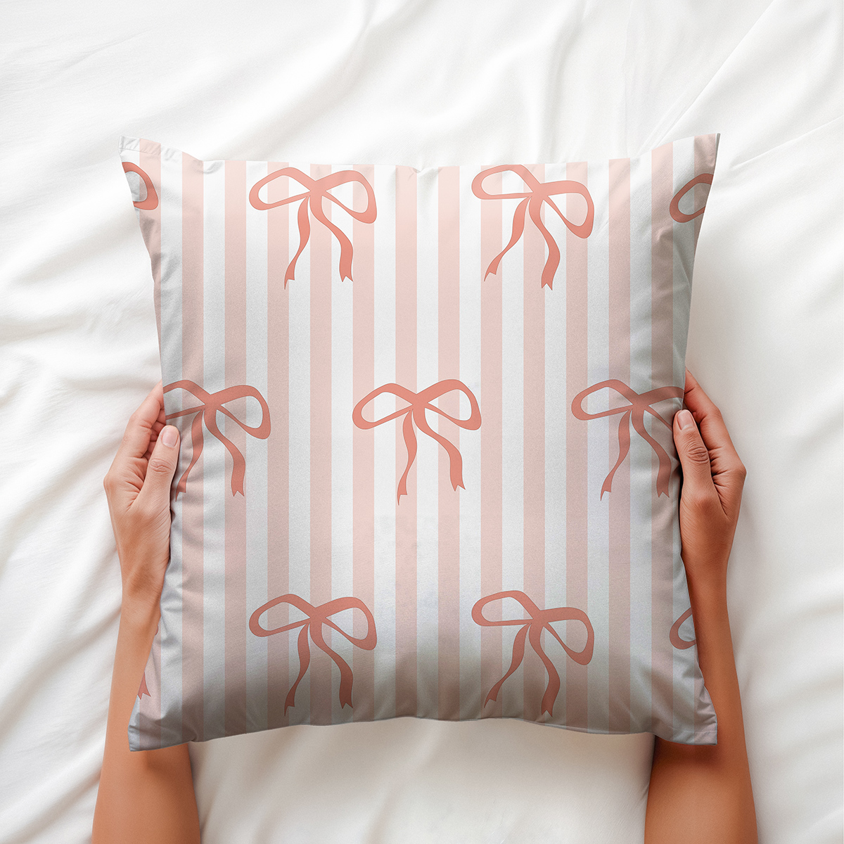 poduszka trzymana dłońmi na jasnej pościeli — widok z góry