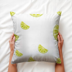 dłoń trzyma poduszkę z motywem limonkowych plasterków na białej pościeli