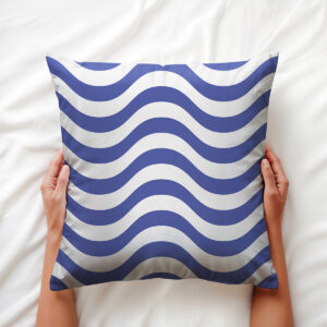 Dłoń trzymająca poduszkę z motywem morskich fal, widok z góry na łóżku