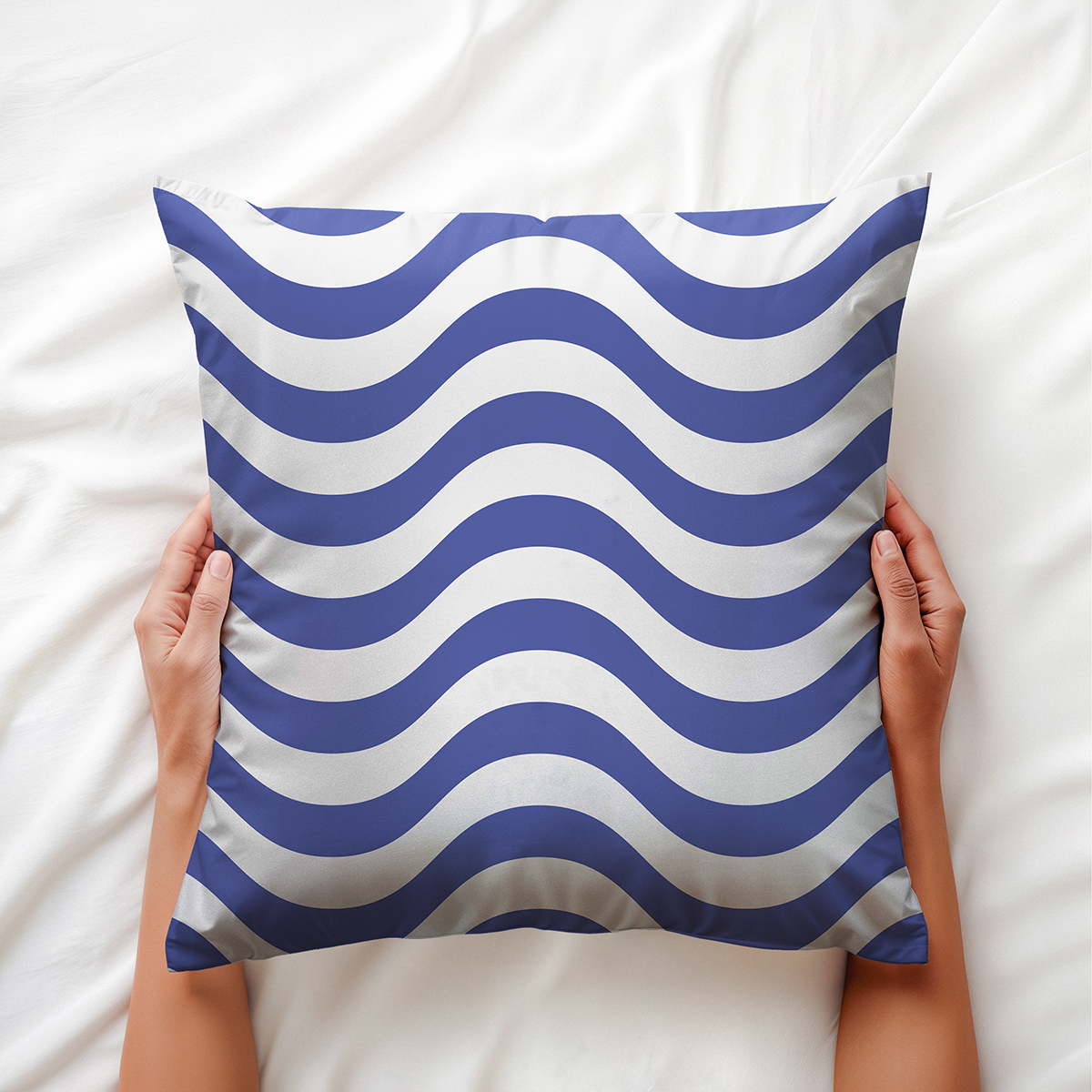 Dłoń trzymająca poduszkę z motywem morskich fal, widok z góry na łóżku