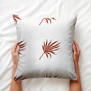 widok od góry na poduszkę trzymaną w dłoniach z rysunkowym motywem palmowych liści — detal wzoru