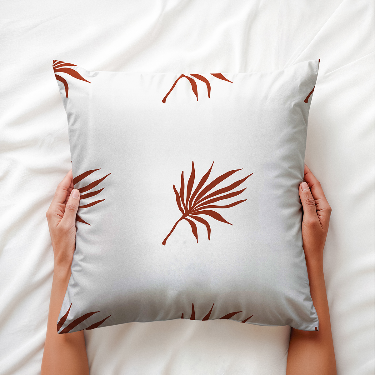 widok od góry na poduszkę trzymaną w dłoniach z rysunkowym motywem palmowych liści — detal wzoru