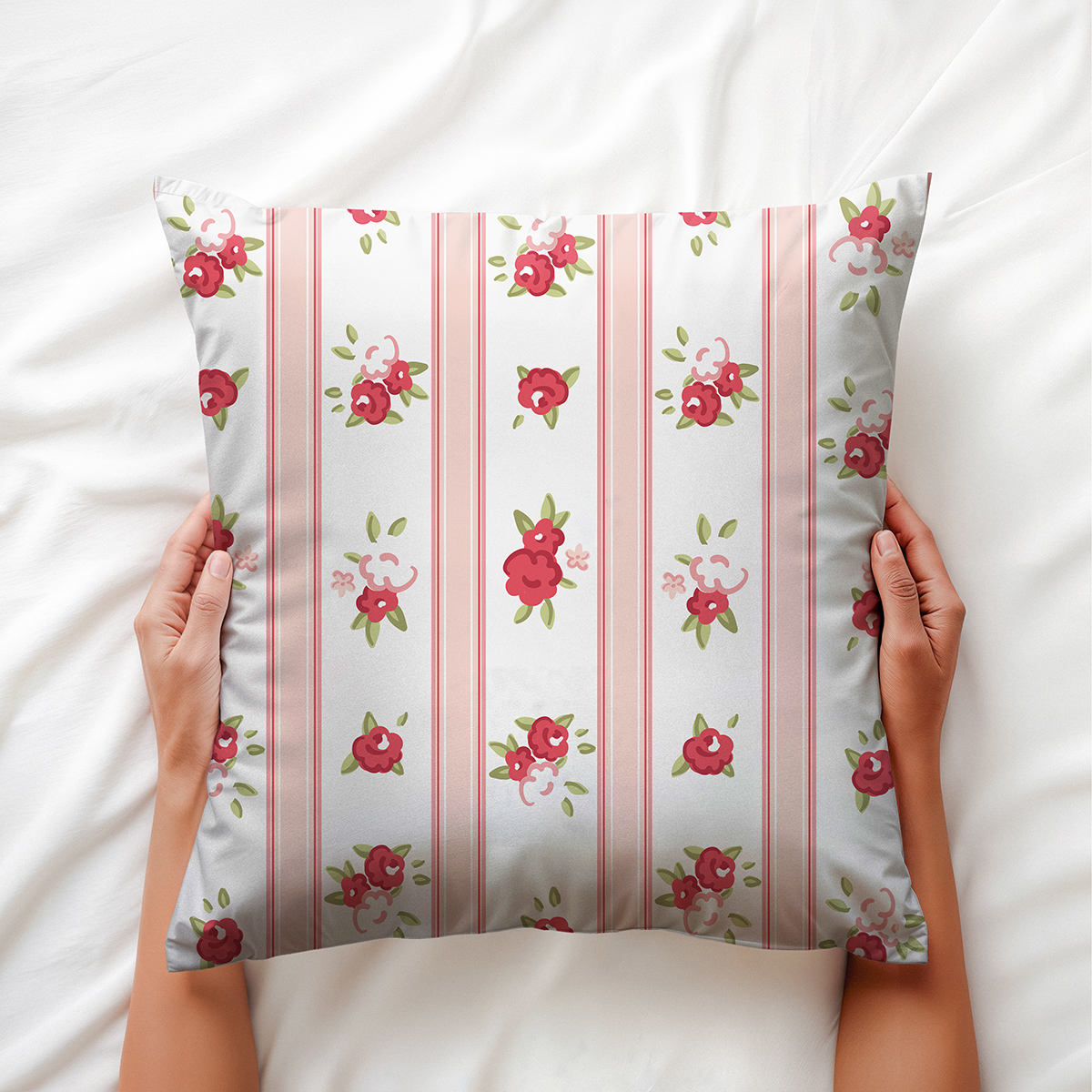 Widok z góry: poduszka trzymana dłońmi na jasnej pościeli, widoczne detale wzoru i kolory