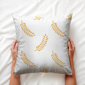 widok z góry poduszki trzymanej dłońmi, uwidaczniający fakturę tkaniny i złote liście