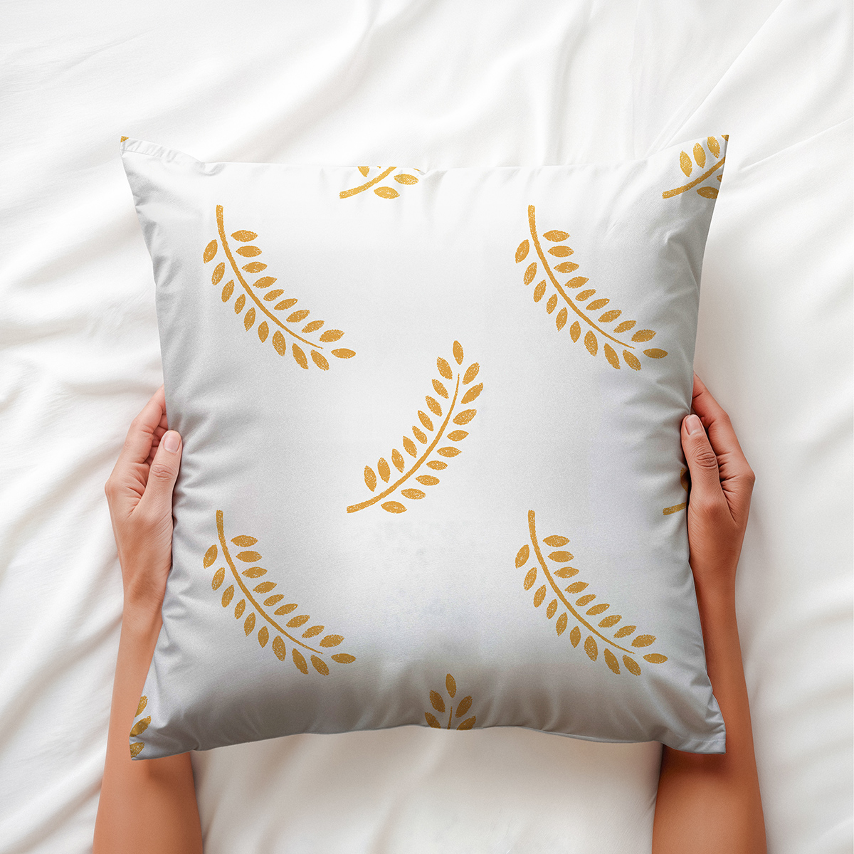 widok z góry poduszki trzymanej dłońmi, uwidaczniający fakturę tkaniny i złote liście