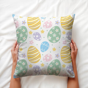 Poduszka trzymana dłońmi, widoczny wzór pisanek i drobnych kwiatów