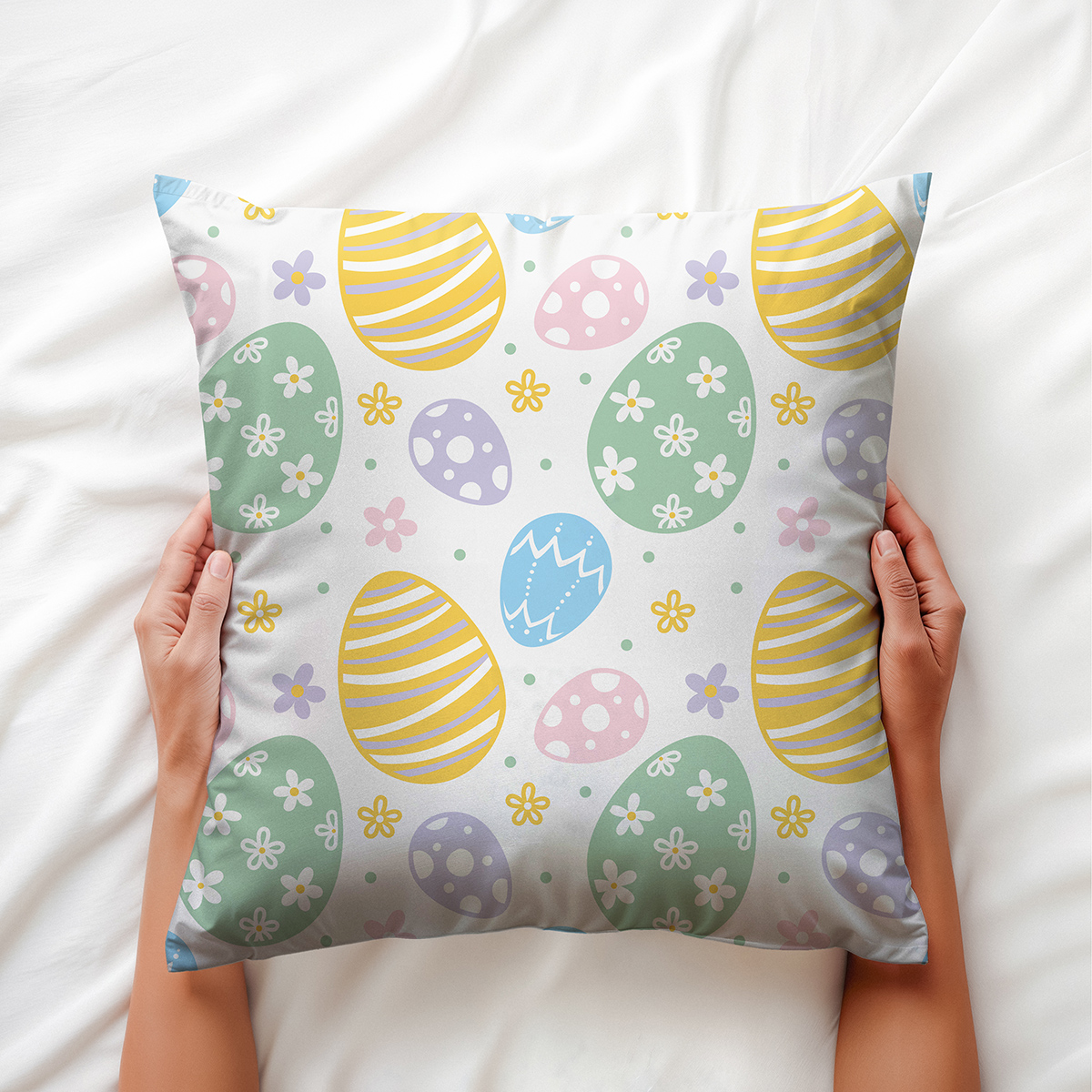 Poduszka trzymana dłońmi, widoczny wzór pisanek i drobnych kwiatów