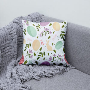 Poduszka z pastelowymi jajkami i kwiatami ułożona na kanapie