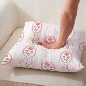 Ręka naciskająca poduszkę, uwidoczniony miękki materiał i powtarzalny motyw pisanek z kwiatami