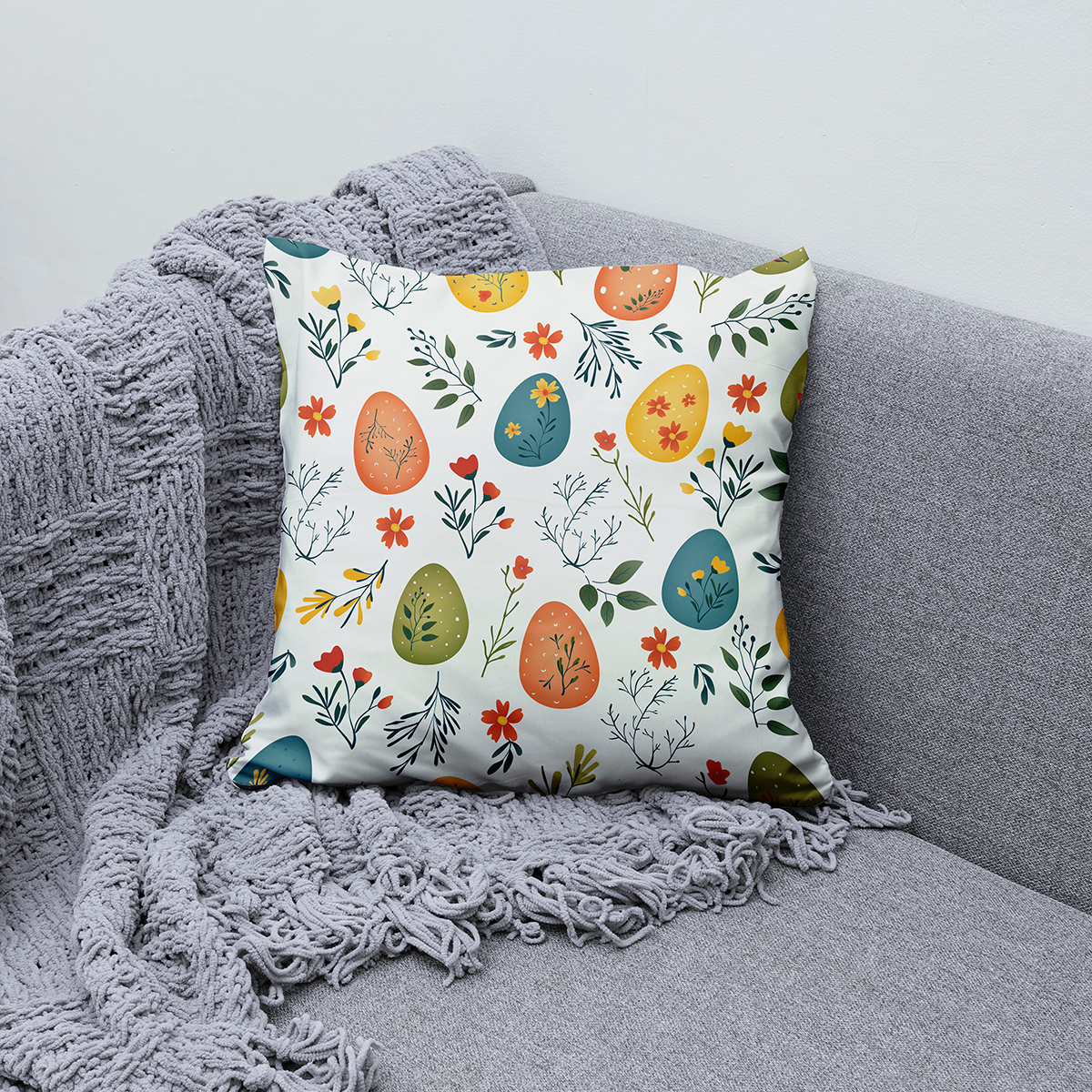 Poduszka ułożona na sofie obok pledu, widoczny całościowy wzór