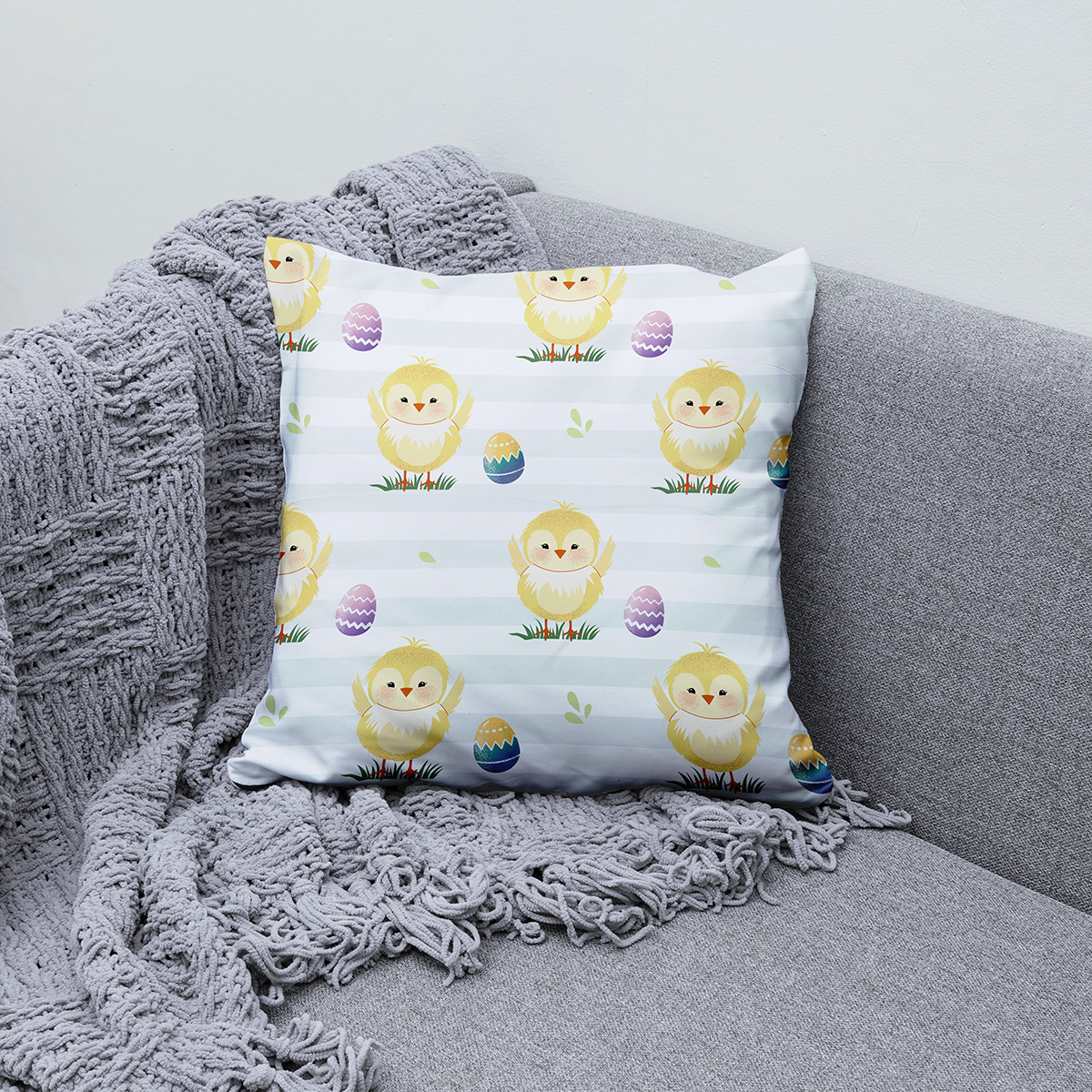 Poduszka ułożona na sofie w aranżacji z jasnym kocem i podkreślającym wnętrze stylem