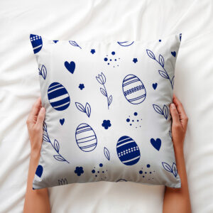 Poduszka trzymana w dłoniach, widoczny wzór pisanek, serc i delikatnych liści