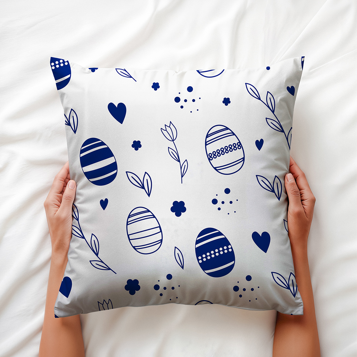 Poduszka trzymana w dłoniach, widoczny wzór pisanek, serc i delikatnych liści