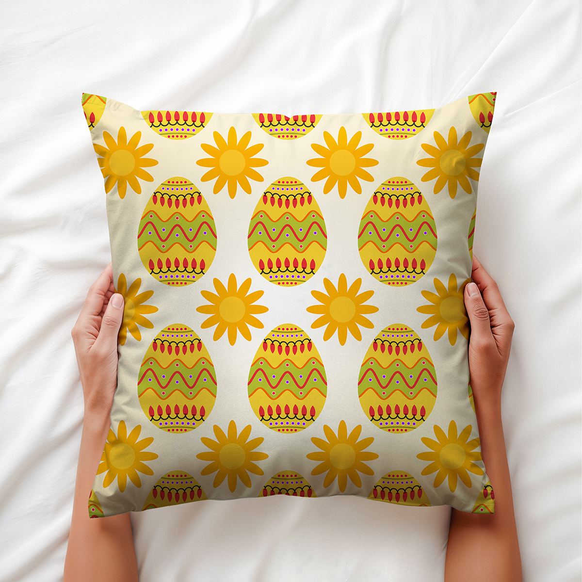 Poduszka trzymana w dłoniach, widoczny wzór dekoracyjnych pisanek i żółtych słoneczek