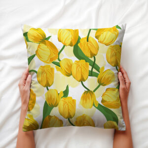 Dłoń trzymająca poduszkę z motywem żółtych tulipanów, widok z góry