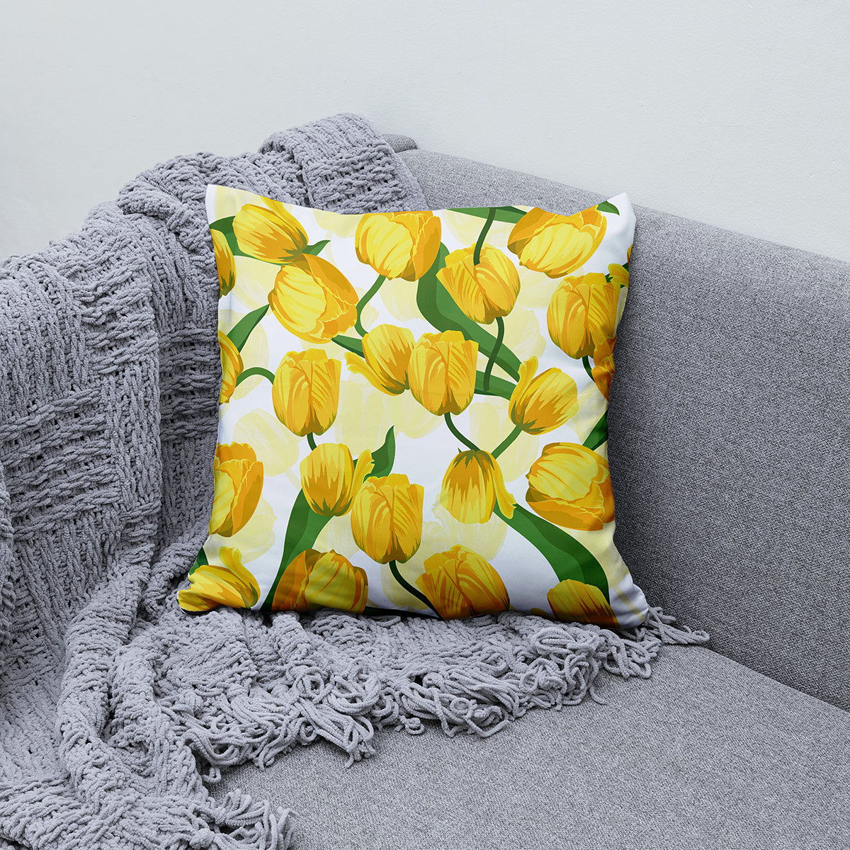 Poduszka z żółtymi tulipanami ułożona na kanapie jako dekoracja