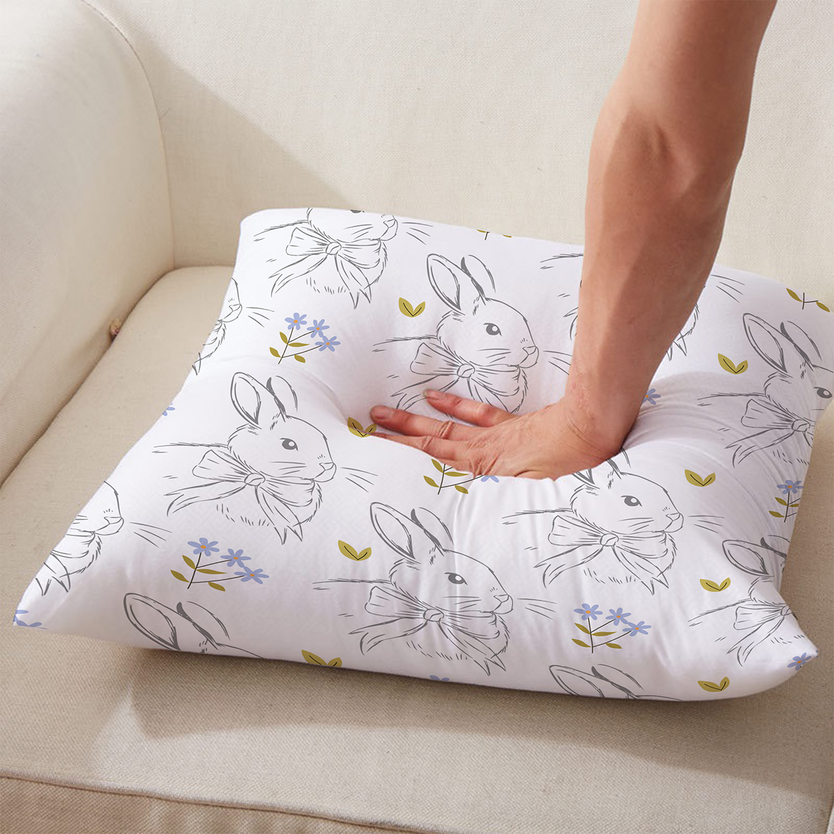 Poduszka wielkanocna w króliczki z wkładem na kremowym fotelu