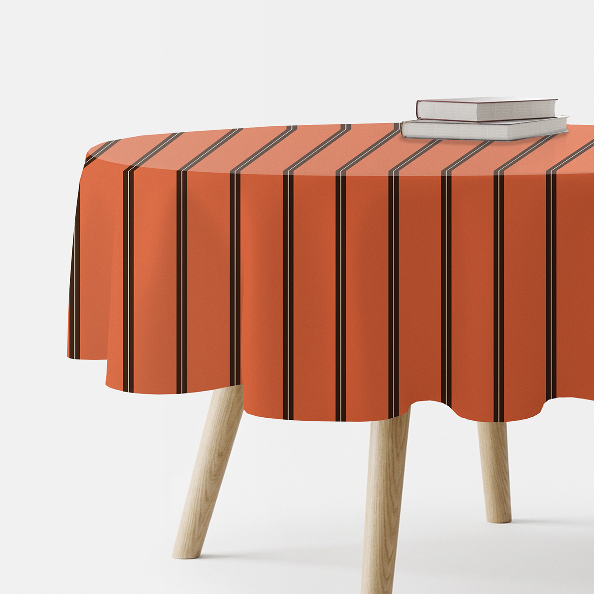 okrągły obrus w ceglastym kolorze z pionowymi brązowymi paskami na stole z książkami