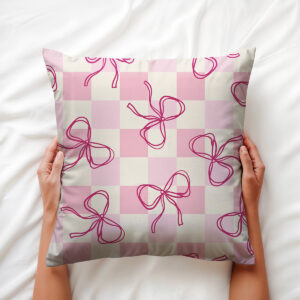 dłoń trzyma poduszkę na białej pościeli, widok na wzór kratki i rozmieszczone kokardki
