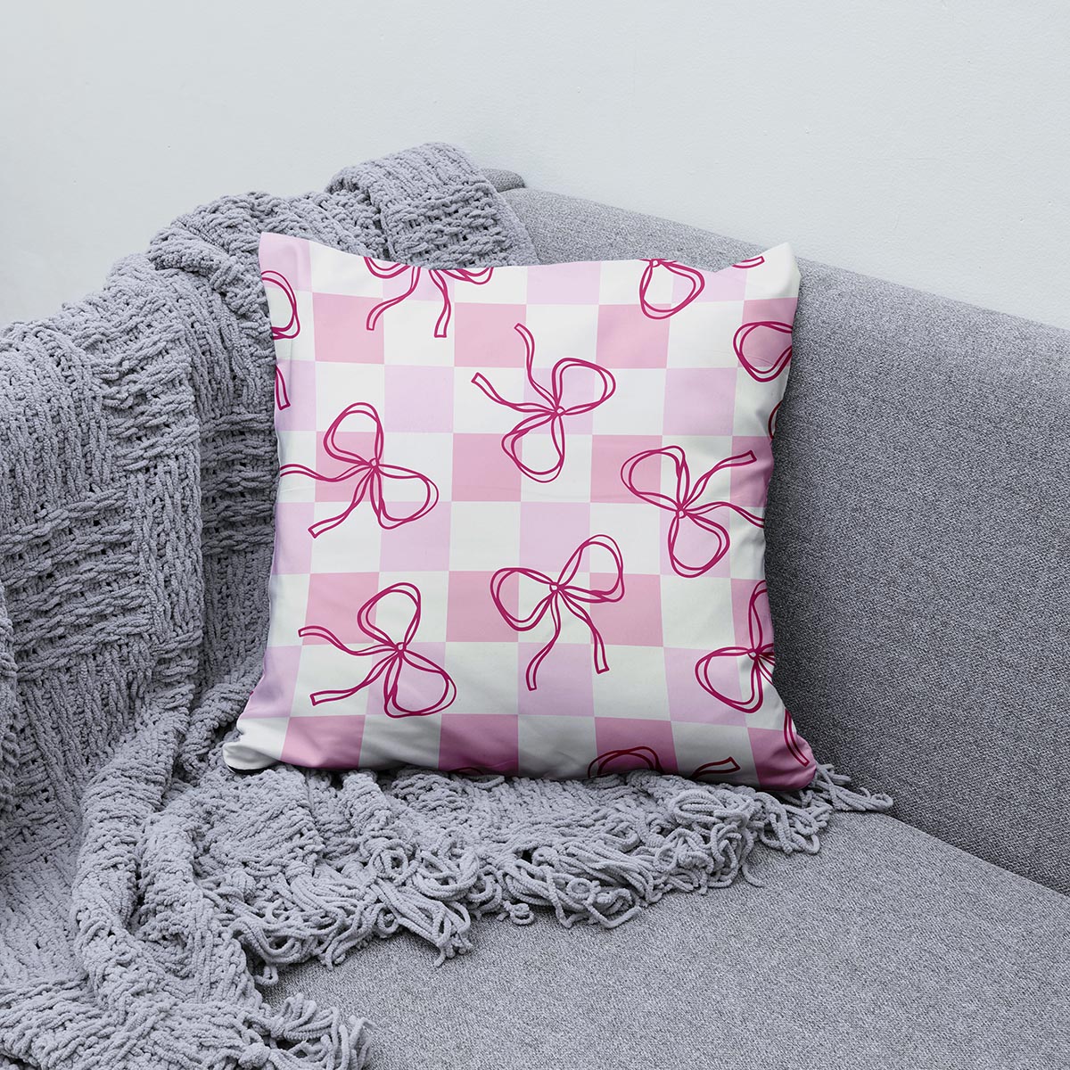 poduszka ozdobna ułożona na szarej sofie obok plecionej narzuty