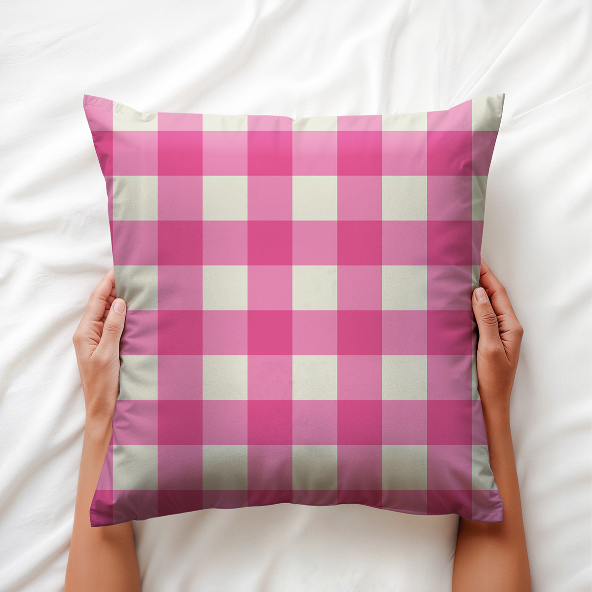 Dłonie trzymające poduszkę dekoracyjną w różowo-kremową kratę na pościeli
