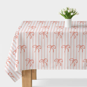 obrus z pionowymi pasami i łososiowymi kokardkami na stole z białym wazonem z tulipanami