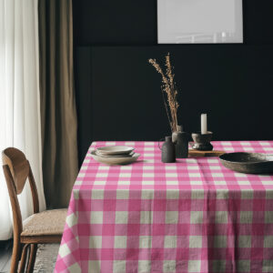 Stół nakryty obrusem w kratę w różu i kremie z ciemnym tłem i ceramiczną zastawą