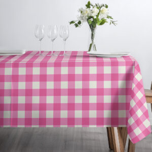 Stół udekorowany szkłem i talerzami na obrusie w różową i kremową kratę