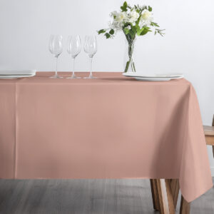 stół udekorowany różowym obrusem z kieliszkami i bukietem kwiatów