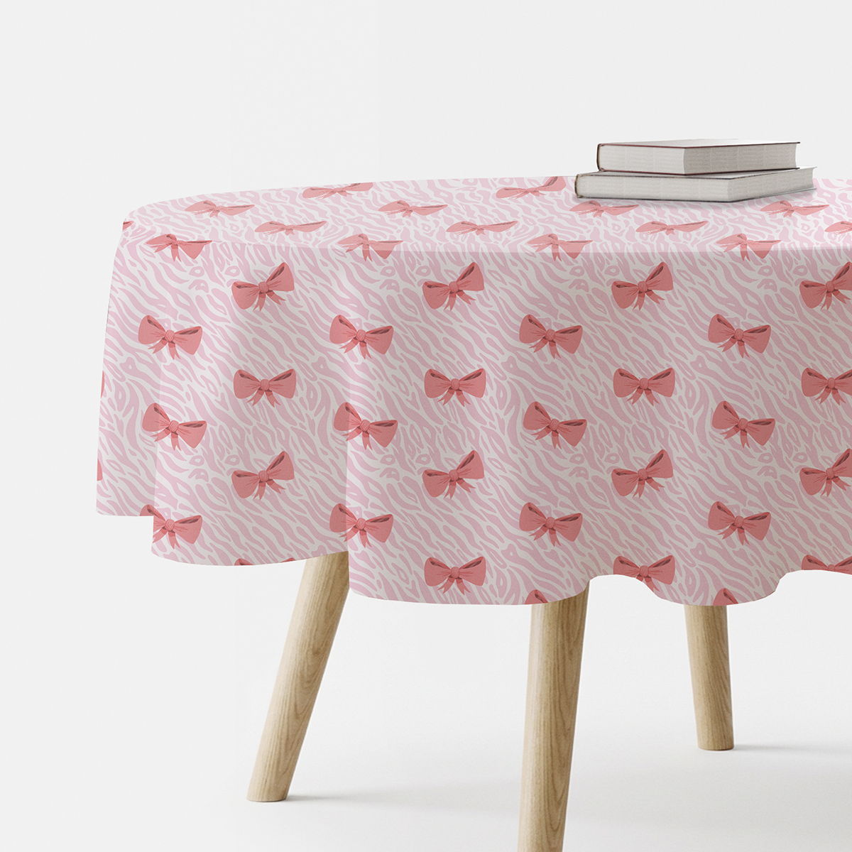 okrągły obrus z nadrukiem różowych kokardek widok z boku z książkami na stole