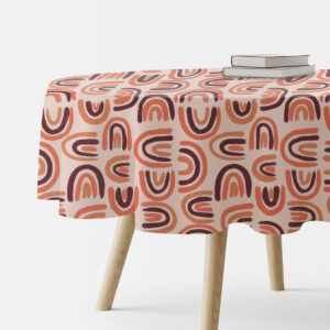 Okrągły obrus z motywem malowanych łuków w ciepłych odcieniach na stole z książkami