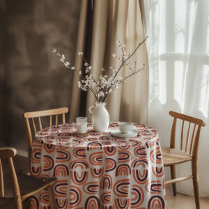 Aranżacja stołu z białym dzbankiem i gałązkami na obrusem w łuki, przy drewnianych krzesłach