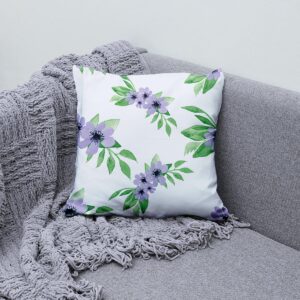 Aranżacja na sofie: poduszka z akwarelowym wzorem fioletowych kwiatów obok szarego koca