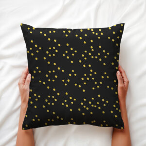 Ręce trzymające poduszkę z drobnym wzorem złotych kropek na łóżku