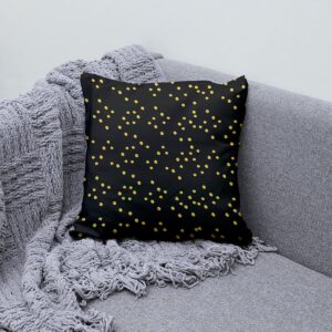 Poduszka ozdobna z złotymi kropkami ułożona na szarej sofie z kocem