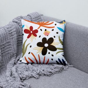 aranżacja na sofie z poduszką o kolorowych, uproszczonych kwiatach