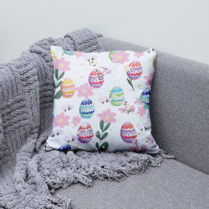 Poduszka z pastelowymi pisankami ułożona na szarym kocu na kanapie, aranżacja wnętrza