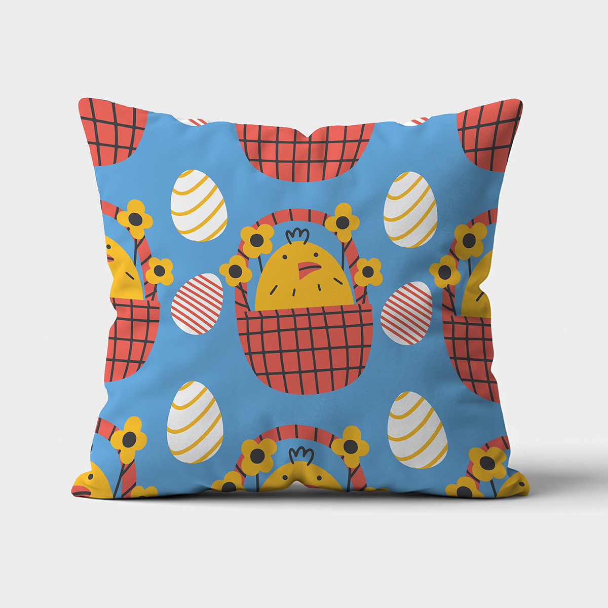 Poduszka z niebieskim tłem i wzorem żółtych kurczaczków w czerwonych koszykach i dekoracyjnymi pisankami, ujęcie frontowe